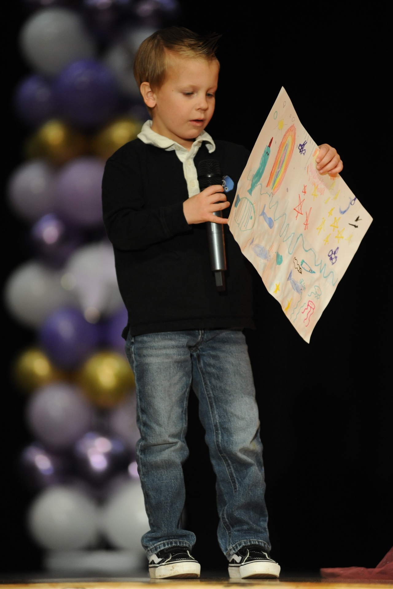 Young performer presenting artwork on stage